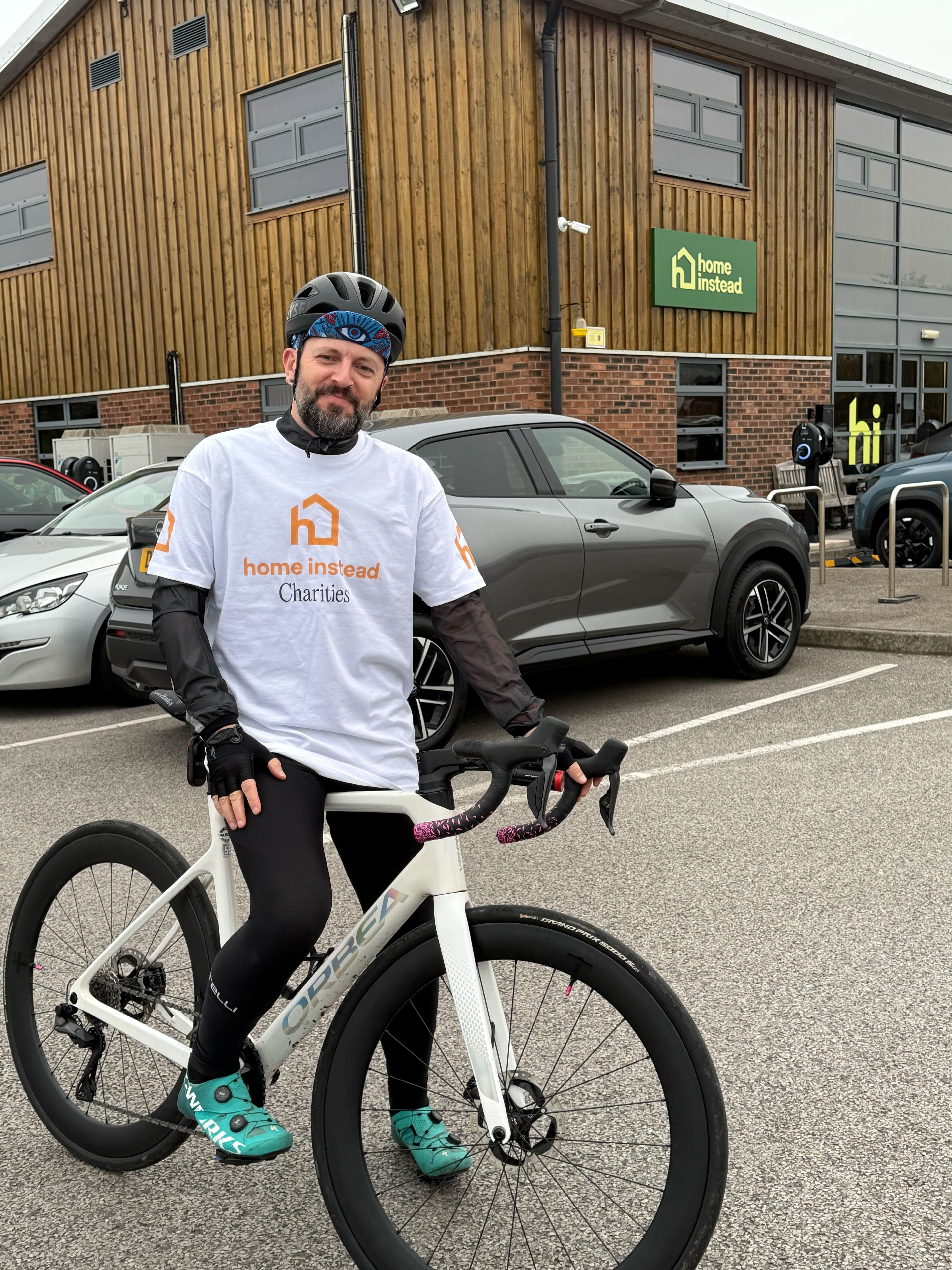 Man on bike outside building with Home instead charities t-shirt on